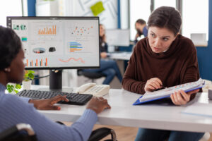 Woman showing Power BI data insights on desktop to student- the impact of Power BI consulting service in USA